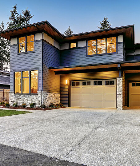 Modern home at dusk blue gray siding with stone accents